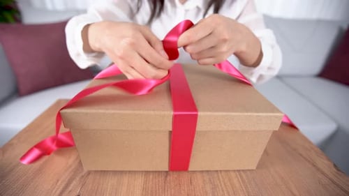 Close Up of Woman Tying Ribbon on Gift Box