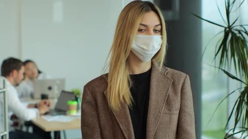 Portrait of Young Businesswoman Wearing Protective Face Mask Standing in Modern Office and Looking