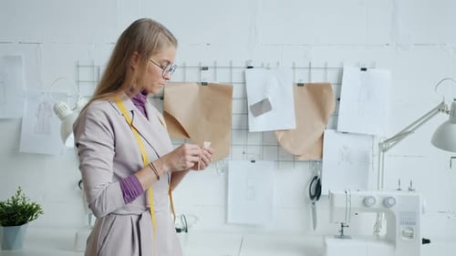 Modern Clothes Designer Choosing Fabric for New Garments Collection Working in Studio
