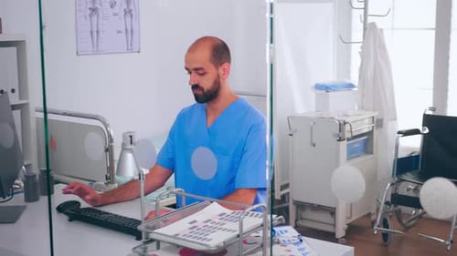 Medical Worker Typing at Computer in Hospital Room