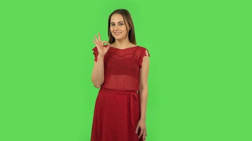 Zartes Mädchen im roten Kleid macht Schild Ok. Greenscreen