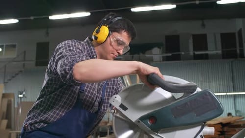 Man cuts wood with chop saw in workshop