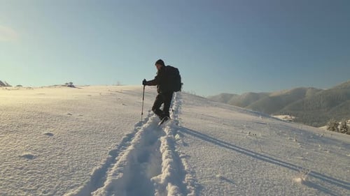 Aerial View of Backpacker Hiking Snowy Mountain Hillside on Cold Winter Day