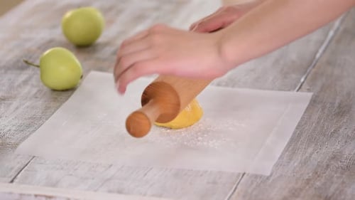Woman Rolling Dough on Parchment Paper