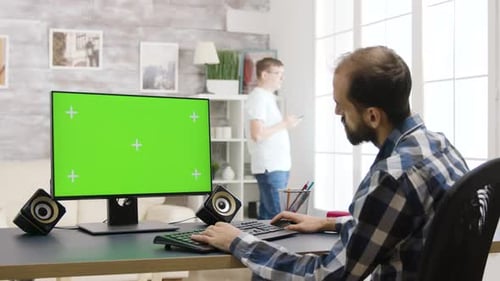 Young Man Working on PC with Green Screen in Bright and Well Lit Living Room
