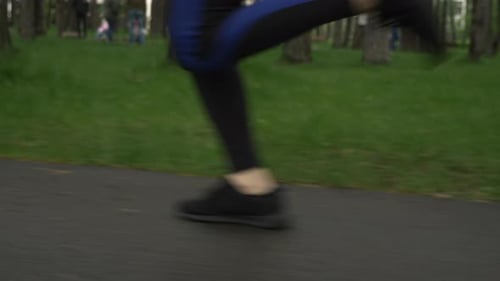 Mujer corredora corriendo sola en el parque de la ciudad después de la lluvia, primer plano de los pies.