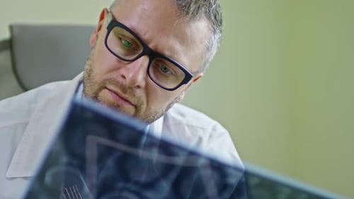 Doctor in Glasses Inspecting MRI Scan of Brain