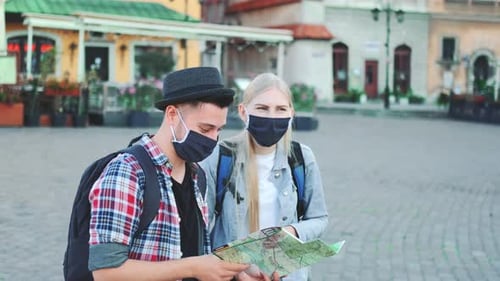 Couple of tourists in masks consult city map