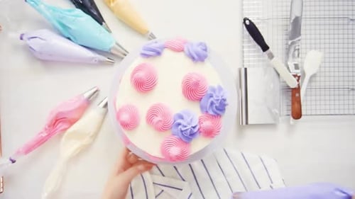 Étape par étape. Vue de dessus. Pâtissier, glaçage à la crème au beurre sur un gâteau à la licorne pour petite fille