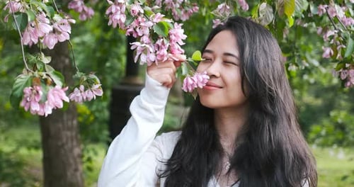Woman Smelling Pink Flowers in Springtime Park