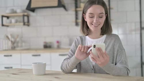 Woman Using Smartphone at Kitchen Table