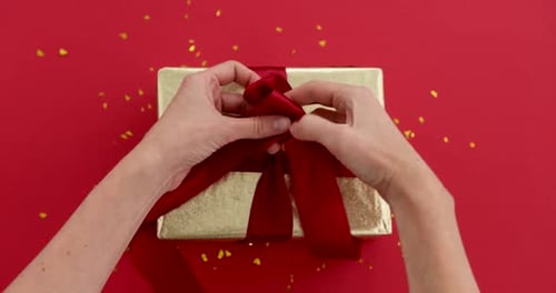 Hands Tying Red Ribbon on Birthday Gift