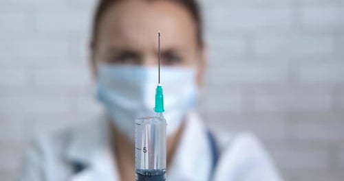 Syringe Needle Close Up with Medical Professional
