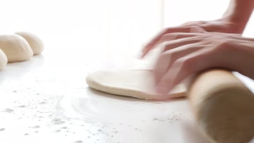 Hands Rolling Dough on White Table