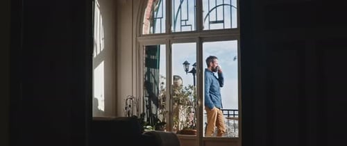 Man Drinks Coffee on Apartment Balcony on Sunny Day