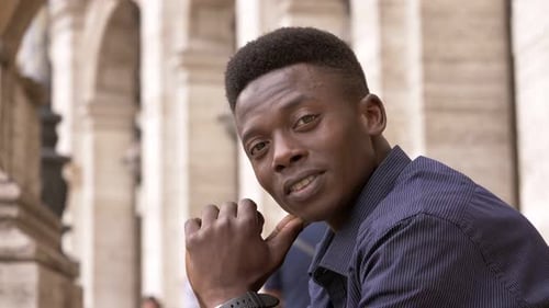 Young Man Smiling, Posing in City with Historic Architecture