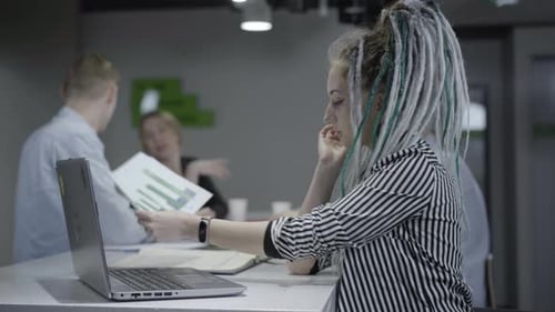 Side View Portrait of Concentrated Millennial Woman Working on Laptop in Office