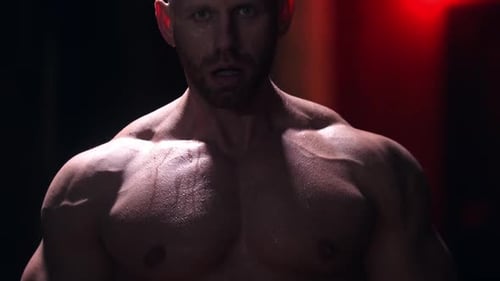 Tough Shirtless Man Covered in Sweat Standing in the Gym and Doing Exercises - Pulling Up a Heavy