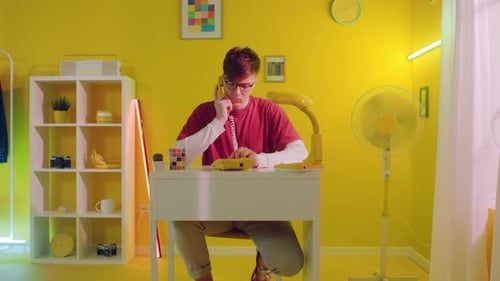 Young Adult Talking on Landline Phone in Yellow Room