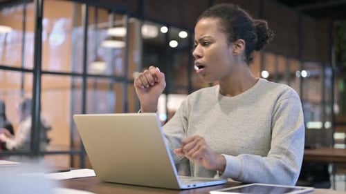 Young Adult Woman Coughing While Using Laptop