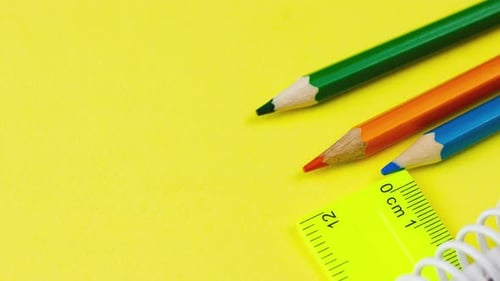 Multicolored Sharp Wooden Colored Pencils Lie on a Pastel Yellow Background with a Ruler
