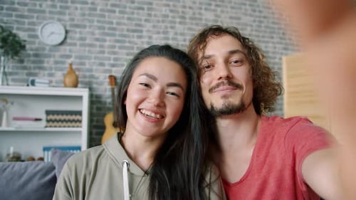 Happy Couple Waving During a Video Call at Home