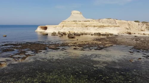An aerial drone shot flies across the Salt Pans and crystal blue water of Gozo Island in Malta.
