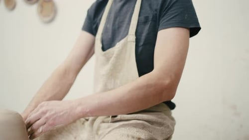 Tracking Shot of Man Potter in Eyeglasses and Apron Working with Clay on Pottery Wheel at Workshop