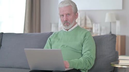 Senior Man Working on Laptop on Sofa