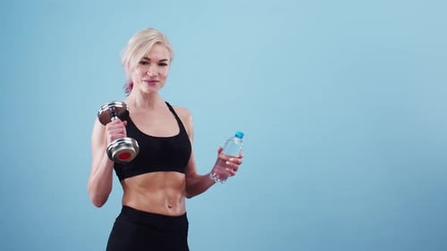 Fit Woman Holding Dumbbell and Water Bottle
