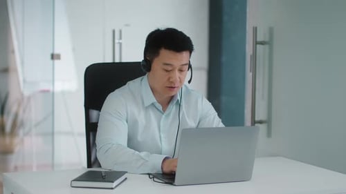 Professional Using Laptop and Headset in Office