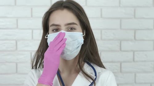 Young Woman Adjusting Surgical Mask in Hospital Setting