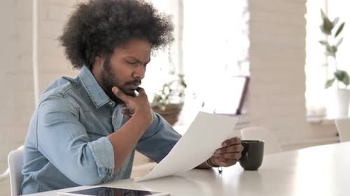 Pensive Creative African Man Reading Documents Brainstorming