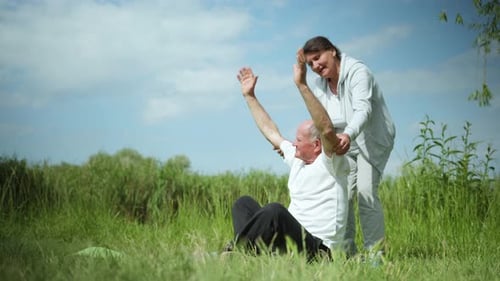 Senior Man Assisted with Stretching Exercise Outdoors
