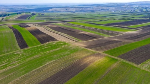 Über landwirtschaftlich gepflügten Feldern fliegen
