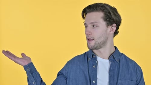 Young Adult Presenting, Smiling on Yellow Background