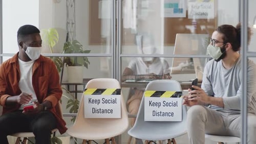 Two Male Office Workers in Masks Discussing Social Media on Smartphones