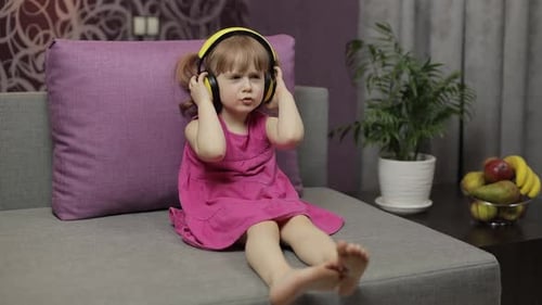 Little Girl Enjoys Music on Yellow Headphones