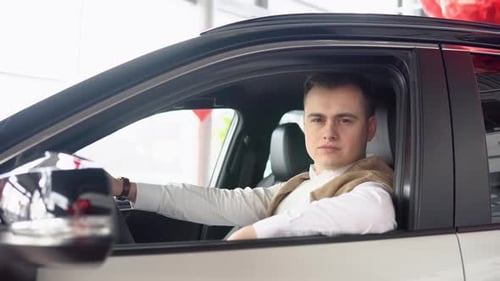 Portrait of a Young Confident Man Sitting in a New Car at a Car Dealership