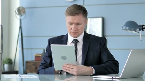 Man in Suit Uses Tablet at Bright Desk