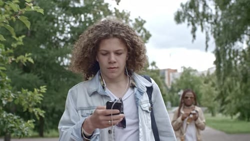 Teenager Listening to Music and Texting on Phone at Walk