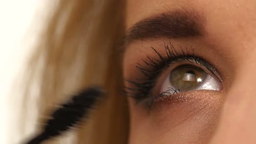 Woman Applying Mascara on Her Long Eyelashes. Close Up