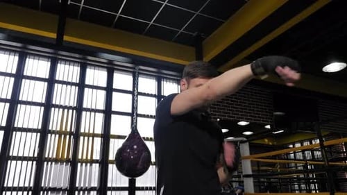 Young Muscular Man Practicing Punches in the Boxing Ring