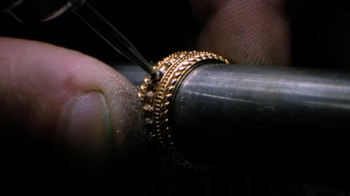 Goldschmied bohrt mit einem Bohrwerkzeug ein Loch in den goldenen Ring