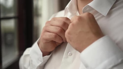 Man Buttoning Up White Dress Shirt for Wedding