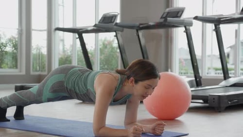 Woman Doing Plank Exercise on Yoga Mat in Gym