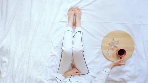 Vue de dessus : Femme fumeuse assise sur son lit