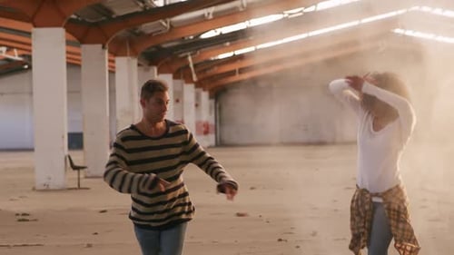 Des danseurs dans un entrepôt vide