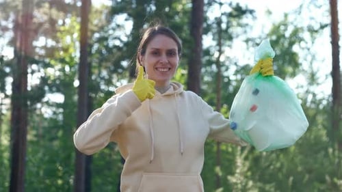 Woman Holding Litter Bag in Forest Gives Thumbs Up