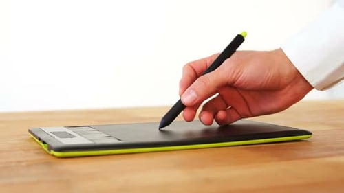 Hand Using Stylus on Graphics Tablet in Workplace